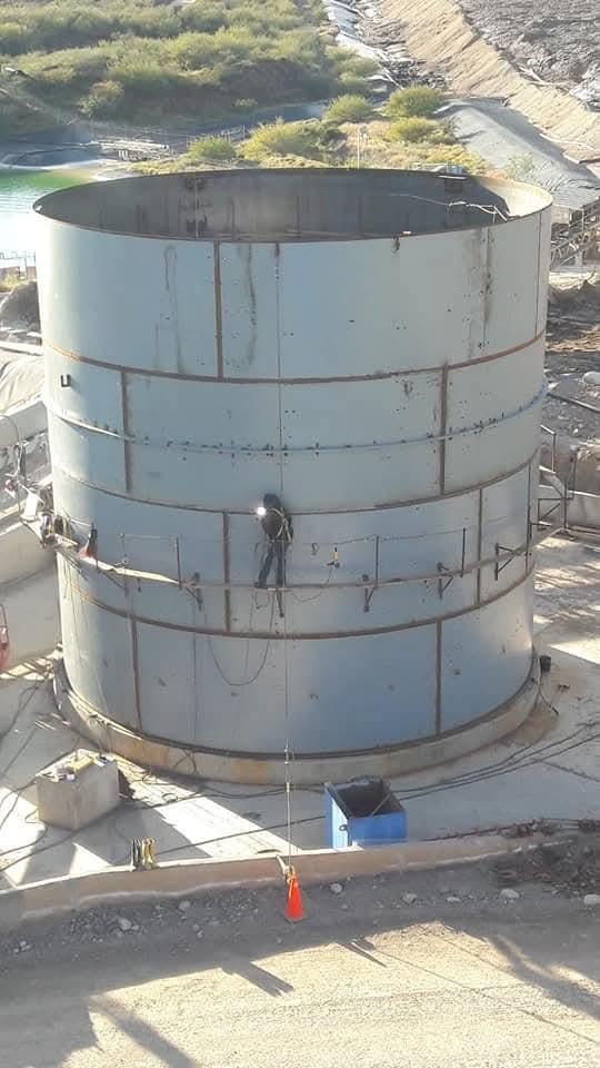 Soldador en rappel sobre tanque industrial